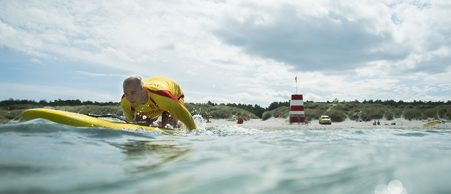Mandlig livredder på surfbræt i vandet