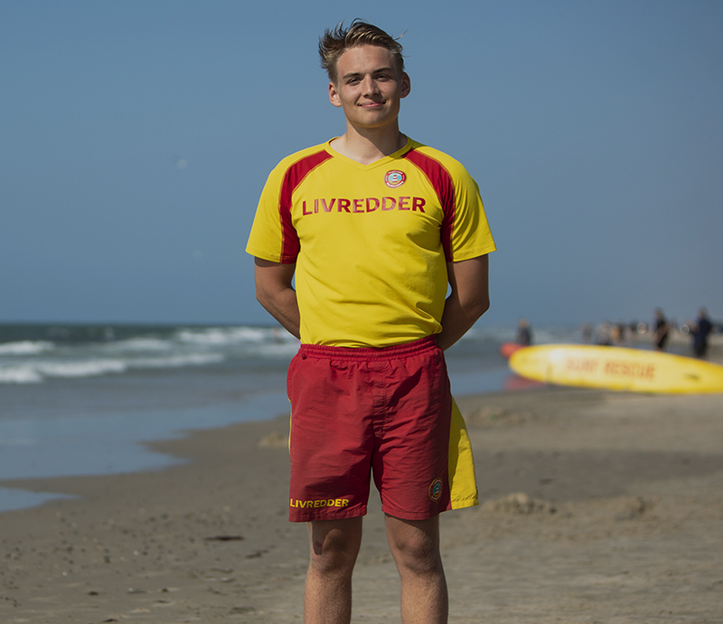 Livredder på stranden med ryggen til