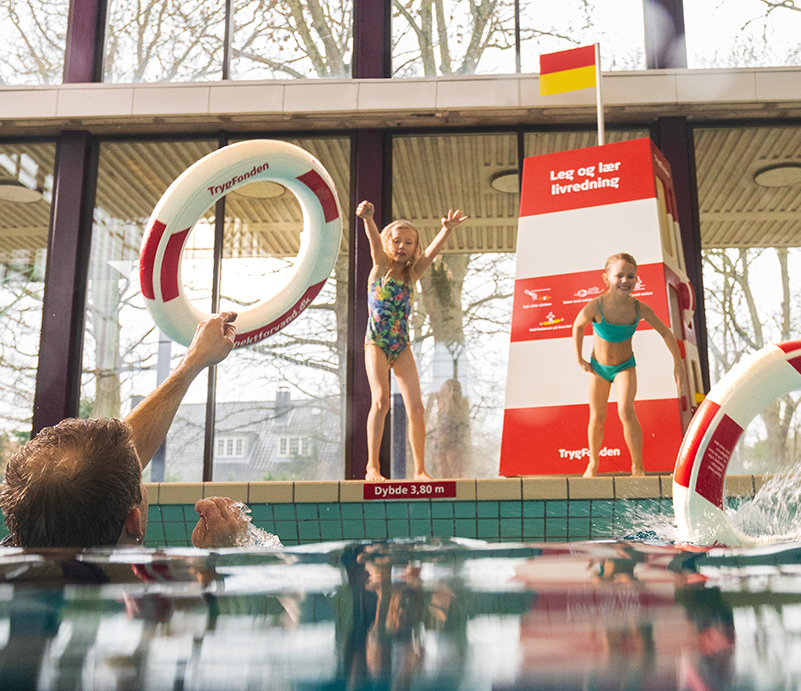 Børn der kaster redningskranse i vandet i svømmehallen