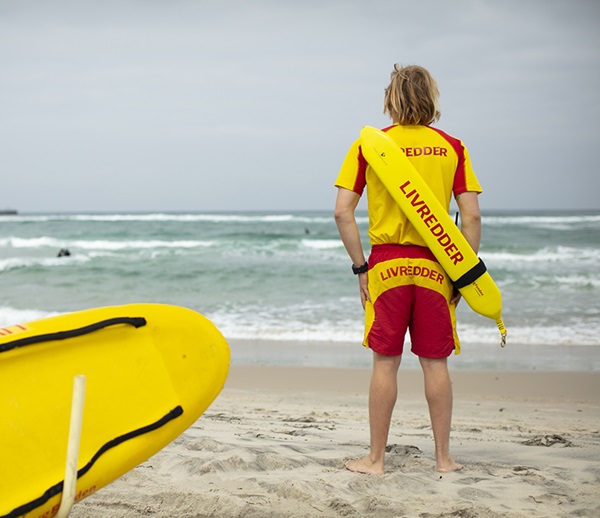 Livredder på stranden med ryggen til