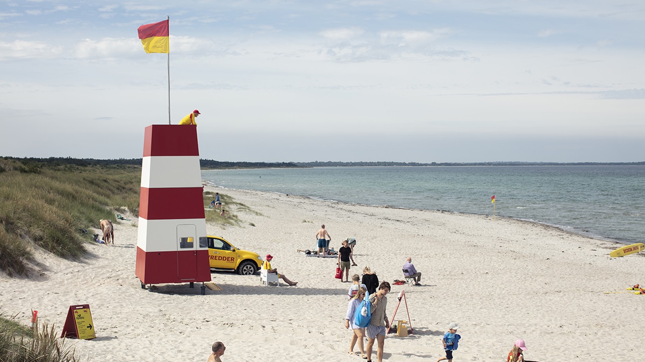 Livreddertårn på stranden med mennesker og livredder omkring